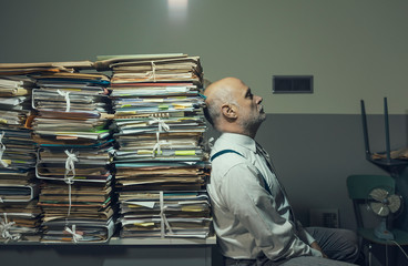 Sad businessman sitting next to a lot of paperwork