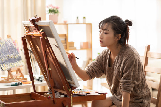 Young Chinese Woman Painting At Home