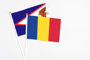 Romania and American Samoa stick flags on white background. High quality fabric, miniature national flag. Peaceful global concept.White floor for copy space.