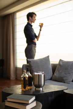 Young Chinese businessman drinking alcohol in front of window