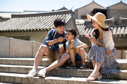 Happy young Chinese family eating ice cream outside