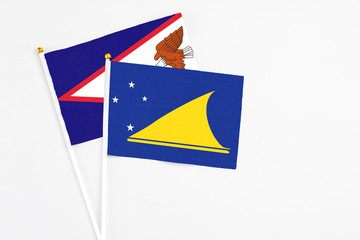 Tokelau and American Samoa stick flags on white background. High quality fabric, miniature national flag. Peaceful global concept.White floor for copy space.