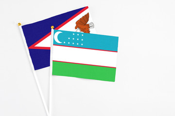 Uzbekistan and American Samoa stick flags on white background. High quality fabric, miniature national flag. Peaceful global concept.White floor for copy space.