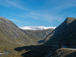Leirdalen Valley with snow capped mountain peaks, forests, wild river stream and road 55 scenic route,Norway. .Nature in the Jotunheimen National park, Norway. Blue sky background