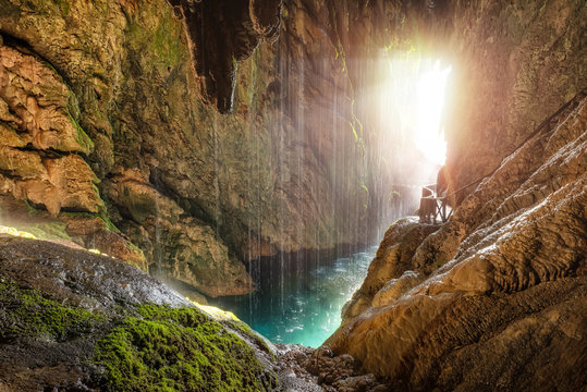 Scenic tropical cave with underground river and pathway with railing in sunlight
