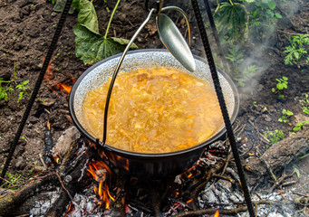 Cooking traditional Hungarian goulash soup in a cauldron outdoors