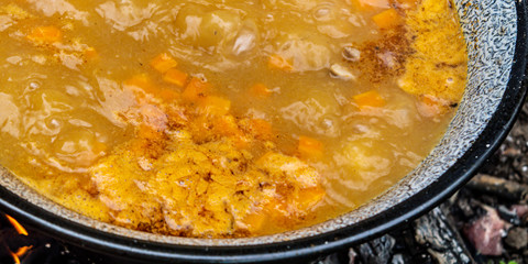 Cooking traditional Hungarian goulash soup in a cauldron outdoors