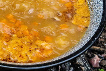 Cooking traditional Hungarian goulash soup in a cauldron outdoors