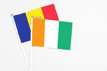 Cote D'Ivoire and Andorra stick flags on white background. High quality fabric, miniature national flag. Peaceful global concept.White floor for copy space.