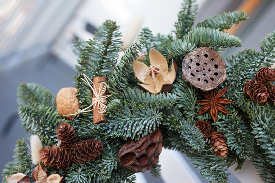 Detailes of Christmas wreath made of natural fir branches hanging on the back of white chair. Wreath with natural ornaments: bumps, walnuts, cinnamon, cones. Christmas decor. - Powered by Adobe
