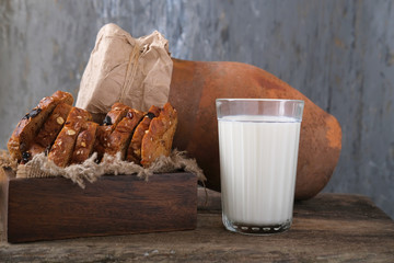 A glass of fresh milk, pieces of rye whole grain bread with prunes and dried apricots and a clay...