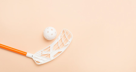 floorball stick and white ball isolated on a light brown background