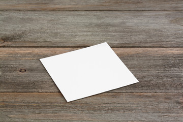 Square empty white business card template on wooden background. Perspective angle with soft shadows. For branding identity, logo design pitches and marketing.