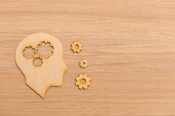 Fototapeta premium Business and design concept - wooden man head silhouette with gear icon on wooden background