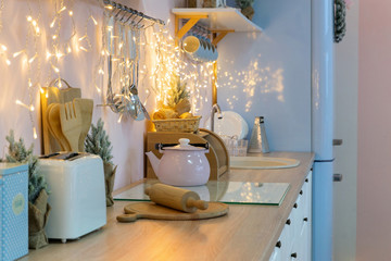 Pink white and blue kitchen interior and kitchenware on holidays, christmas light and decoration garland