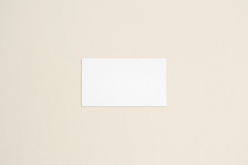 Standard white business card template on bone coloured background. Flat lay, top view. For branding identity, logo design pitches and marketing.