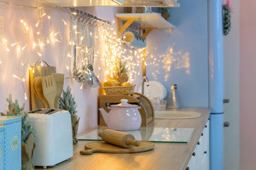 Pink white and blue kitchen interior and kitchenware on holidays, christmas light and decoration garland and wreath