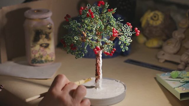 Female artist is painting the handmade wire tree before varnish process