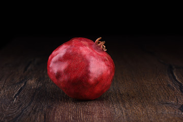 Ripe pomegranate fruit on a wooden table and dark background.