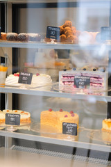 Pastry shop display window of delicatessen store with variety of cakes.