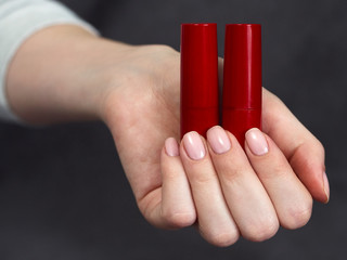 Woman's beauty blogger palm holding bottles and tubes spa professional hi-end cosmetics red...