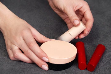 Woman's beauty blogger hands holding bottles and tubes spa professional hi-end cosmetics red...