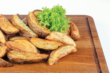 fried potato wedges. home made in rural style and served on on wooden board. healthy organic vegetarian food or beer snack. close up view