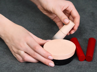 Woman's beauty blogger hands holding bottles and tubes spa professional hi-end cosmetics red...