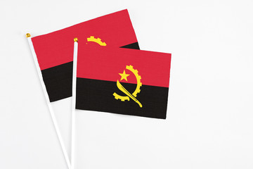 Angola and Angola stick flags on white background. High quality fabric, miniature national flag. Peaceful global concept.White floor for copy space.