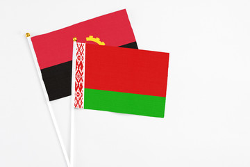 Belarus and Angola stick flags on white background. High quality fabric, miniature national flag. Peaceful global concept.White floor for copy space.