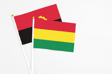 Bolivia and Angola stick flags on white background. High quality fabric, miniature national flag. Peaceful global concept.White floor for copy space.
