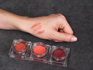 Woman's beauty blogger hand holding professional hi-end tone blush cosmetics set with blurred grey...
