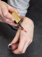 Woman's beauty blogger hands holding bottles and tubes spa professional hi-end liquid lipstick...