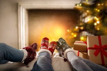 Woman legs with christmas socks and fireplace in home interior. 