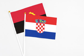 Croatia and Angola stick flags on white background. High quality fabric, miniature national flag. Peaceful global concept.White floor for copy space.