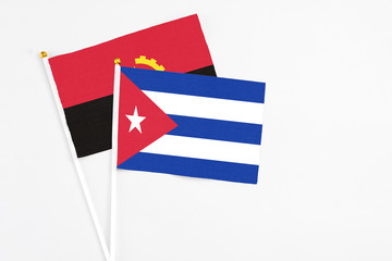 Cuba and Angola stick flags on white background. High quality fabric, miniature national flag. Peaceful global concept.White floor for copy space.