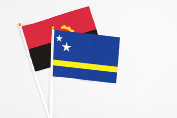 Curacao and Angola stick flags on white background. High quality fabric, miniature national flag. Peaceful global concept.White floor for copy space.