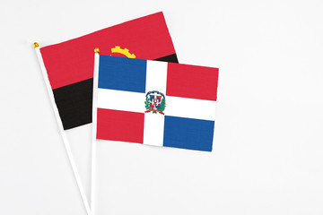 Dominican Republic and Angola stick flags on white background. High quality fabric, miniature national flag. Peaceful global concept.White floor for copy space.