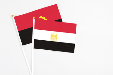 Egypt and Angola stick flags on white background. High quality fabric, miniature national flag. Peaceful global concept.White floor for copy space.