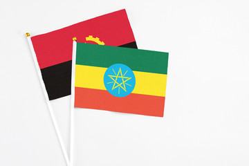 Ethiopia and Angola stick flags on white background. High quality fabric, miniature national flag. Peaceful global concept.White floor for copy space.