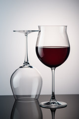 red wine in a wine glass behind it is still a glass on the background