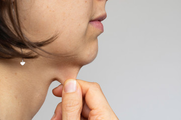 Woman with short hair holding skin on chin isolated on grey background