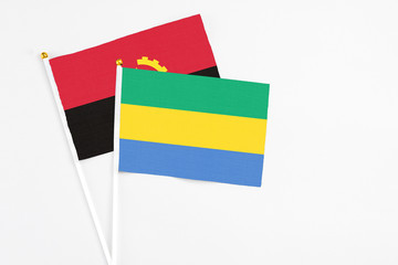 Gabon and Angola stick flags on white background. High quality fabric, miniature national flag. Peaceful global concept.White floor for copy space.