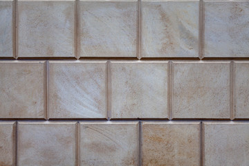 Texture - wall of the building, lined with square stone tiles of neutral color