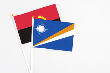 Marshall Islands and Angola stick flags on white background. High quality fabric, miniature national flag. Peaceful global concept.White floor for copy space.