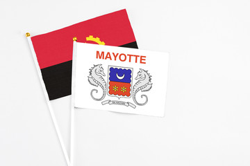 Mayotte and Angola stick flags on white background. High quality fabric, miniature national flag. Peaceful global concept.White floor for copy space.