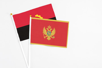 Montenegro and Angola stick flags on white background. High quality fabric, miniature national flag. Peaceful global concept.White floor for copy space.