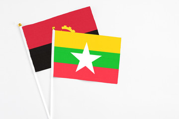 Myanmar and Angola stick flags on white background. High quality fabric, miniature national flag. Peaceful global concept.White floor for copy space.