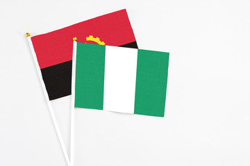 Nigeria and Angola stick flags on white background. High quality fabric, miniature national flag. Peaceful global concept.White floor for copy space.