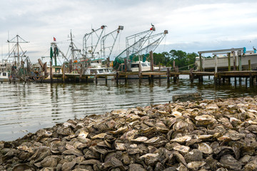 Fishing boats docked in Bon Secour Alabama with piles of oyster shells in foreground